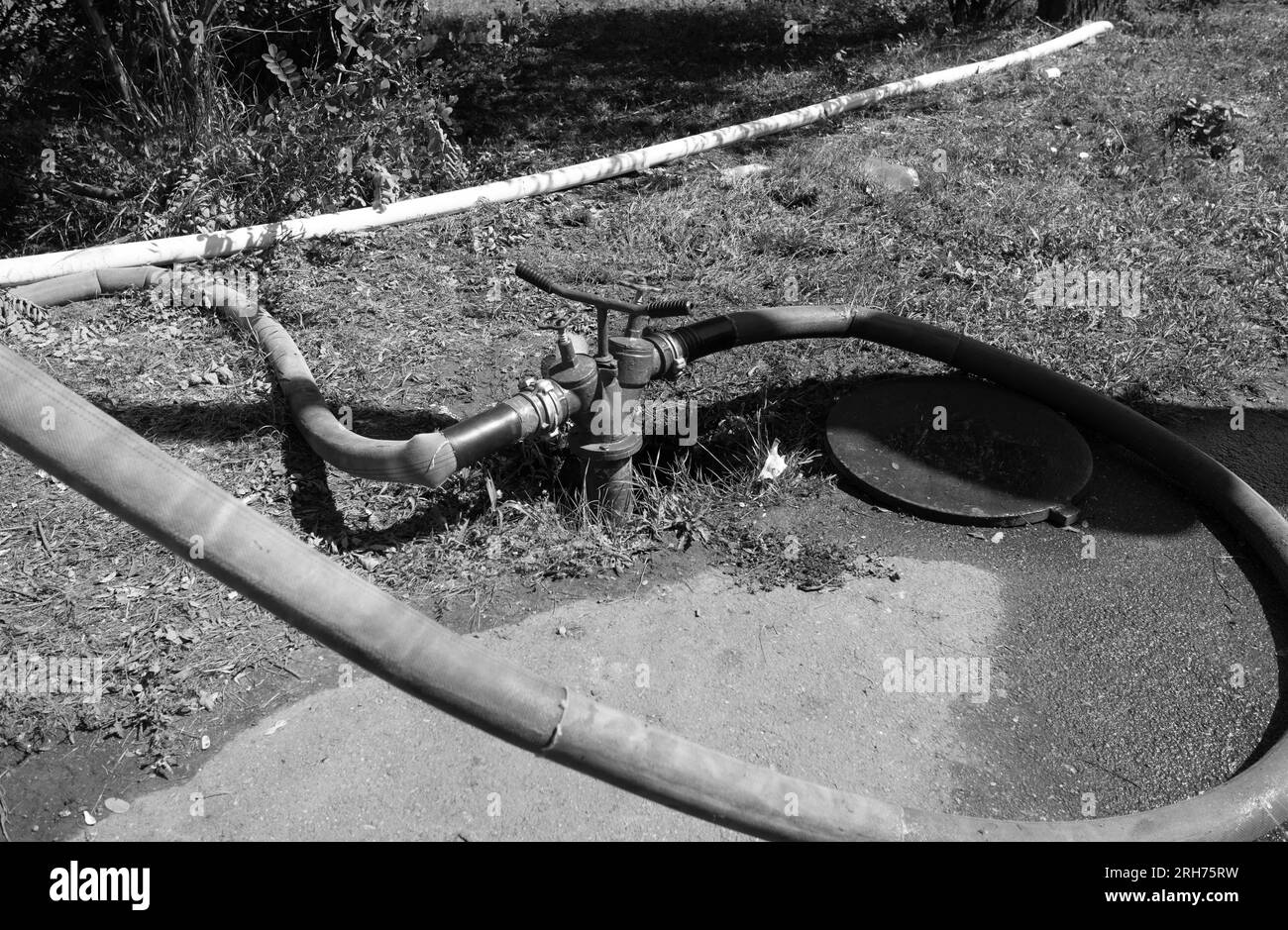 I vecchi tubi flessibili che perdono da una pompa antincendio pompano acqua da un idrante antincendio mentre estinguono un incendio Foto Stock