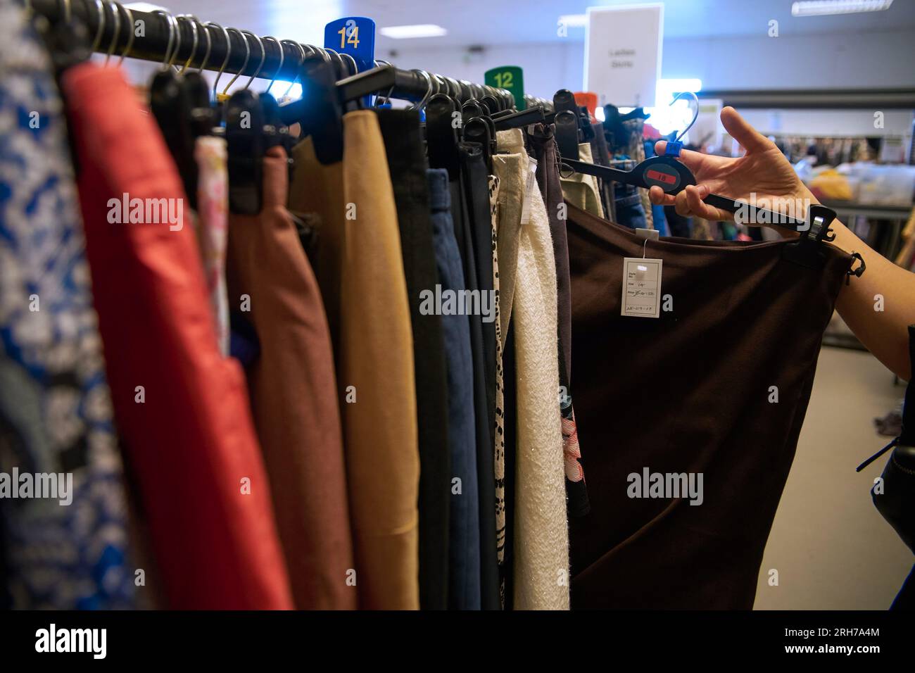 Negozio di beneficenza di seconda mano. Abiti colorati. Foto Stock