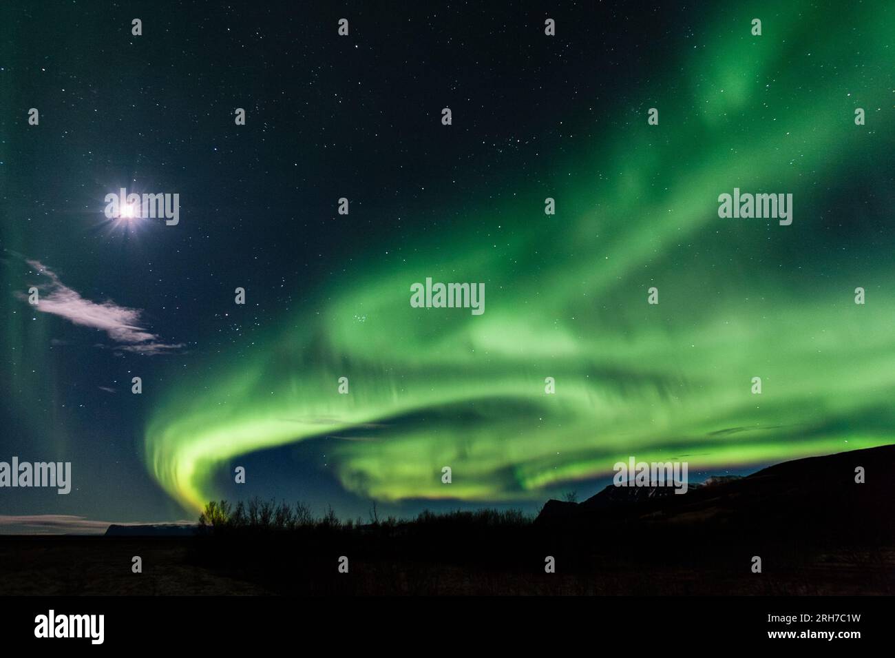 Un cielo notturno limpido nel sud dell'Islanda, con una luna piena e una spettacolare esposizione dell'aurora boreale (Aurora boreale) Foto Stock