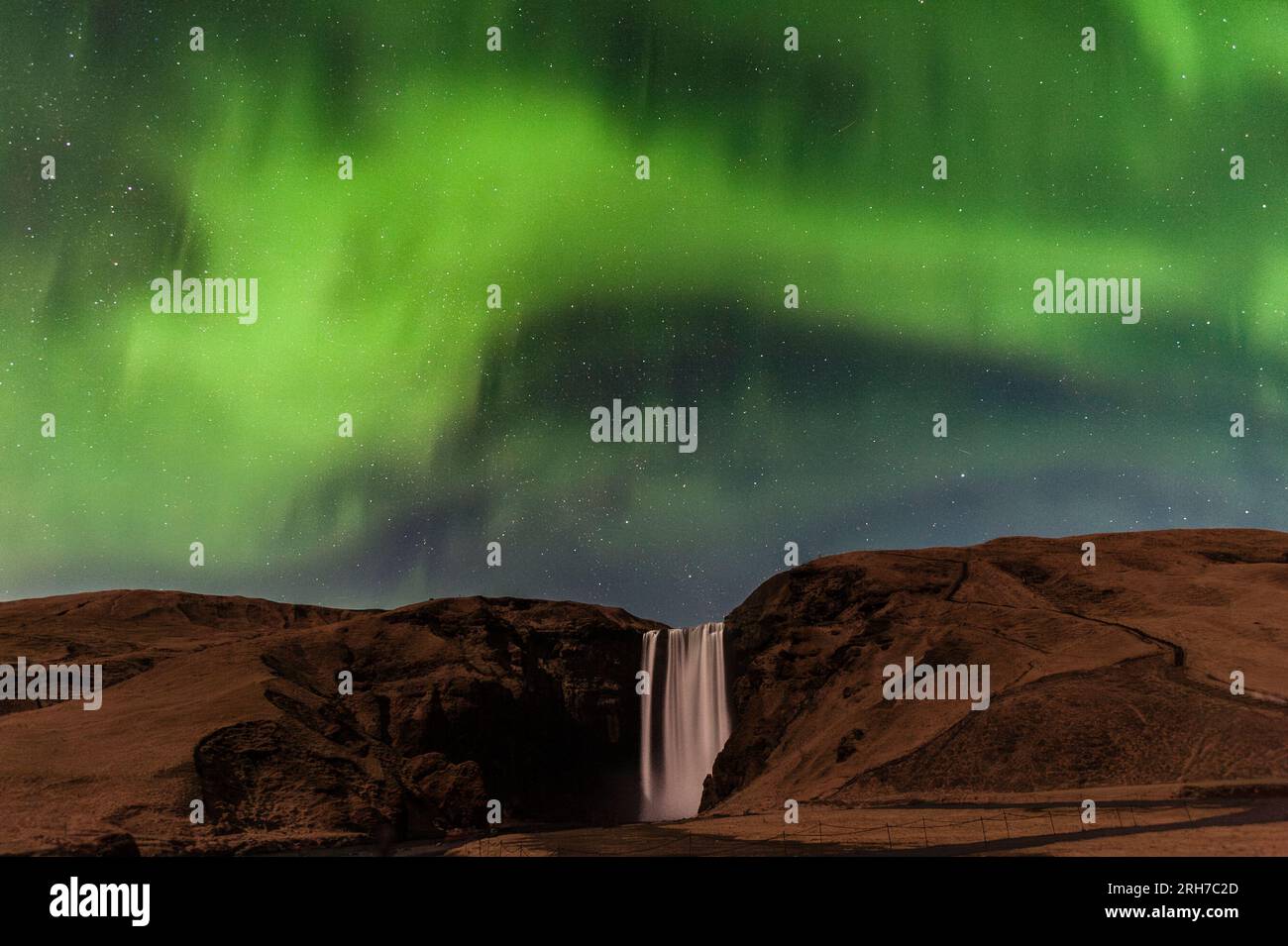 La cascata di 60 m di Skógafoss nel sud dell'Islanda, vista al chiaro di luna di notte sotto un'esposizione dell'aurora boreale (Aurora boreale) Foto Stock