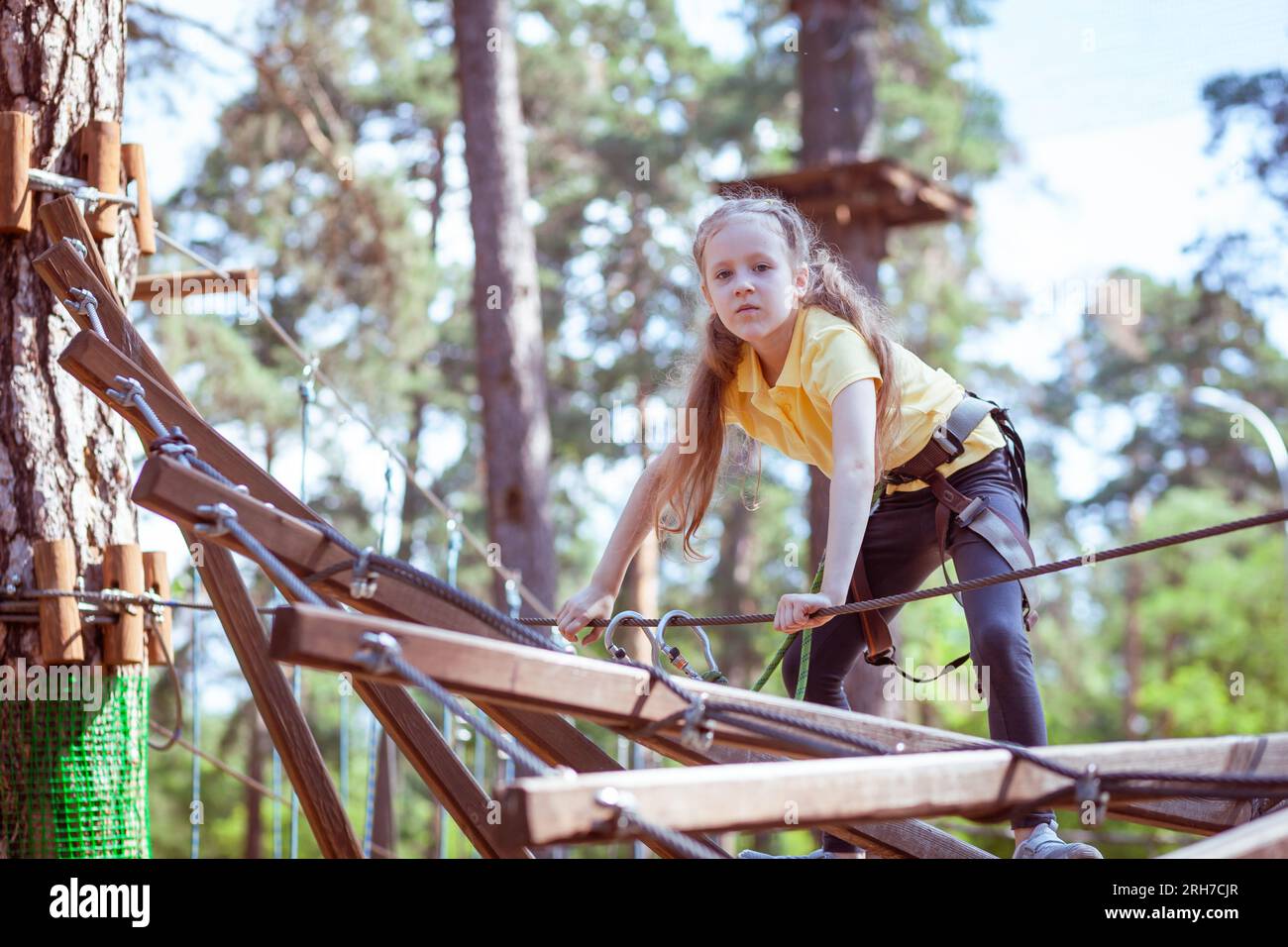 Bambini in un parco avventura nella foresta fatto di corde. Centro di animazione per arrampicata all'aperto per bambini. Parco giochi per bambini e sport con funivia. Foto Stock