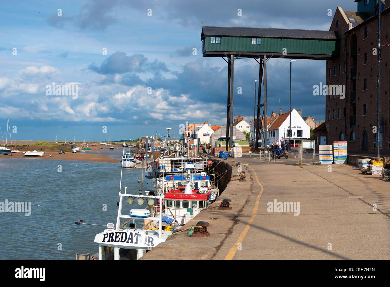 La banchina, in estate, nella città turistica del Norfolk settentrionale di Wells-Next-the-Sea con le sue barche da pesca ormeggiate lungo la bassa marea. Norfolk, Inghilterra Foto Stock