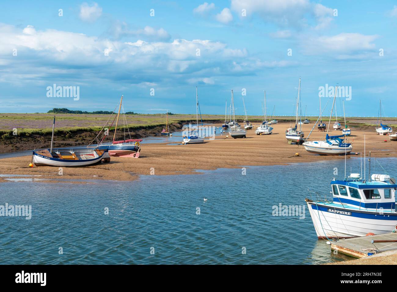 Barche con bassa marea d'estate giacciono sul banco di sabbia di fronte alla località di villeggiatura di Wells-Next-the-Sea, North Norfolk, Inghilterra Foto Stock