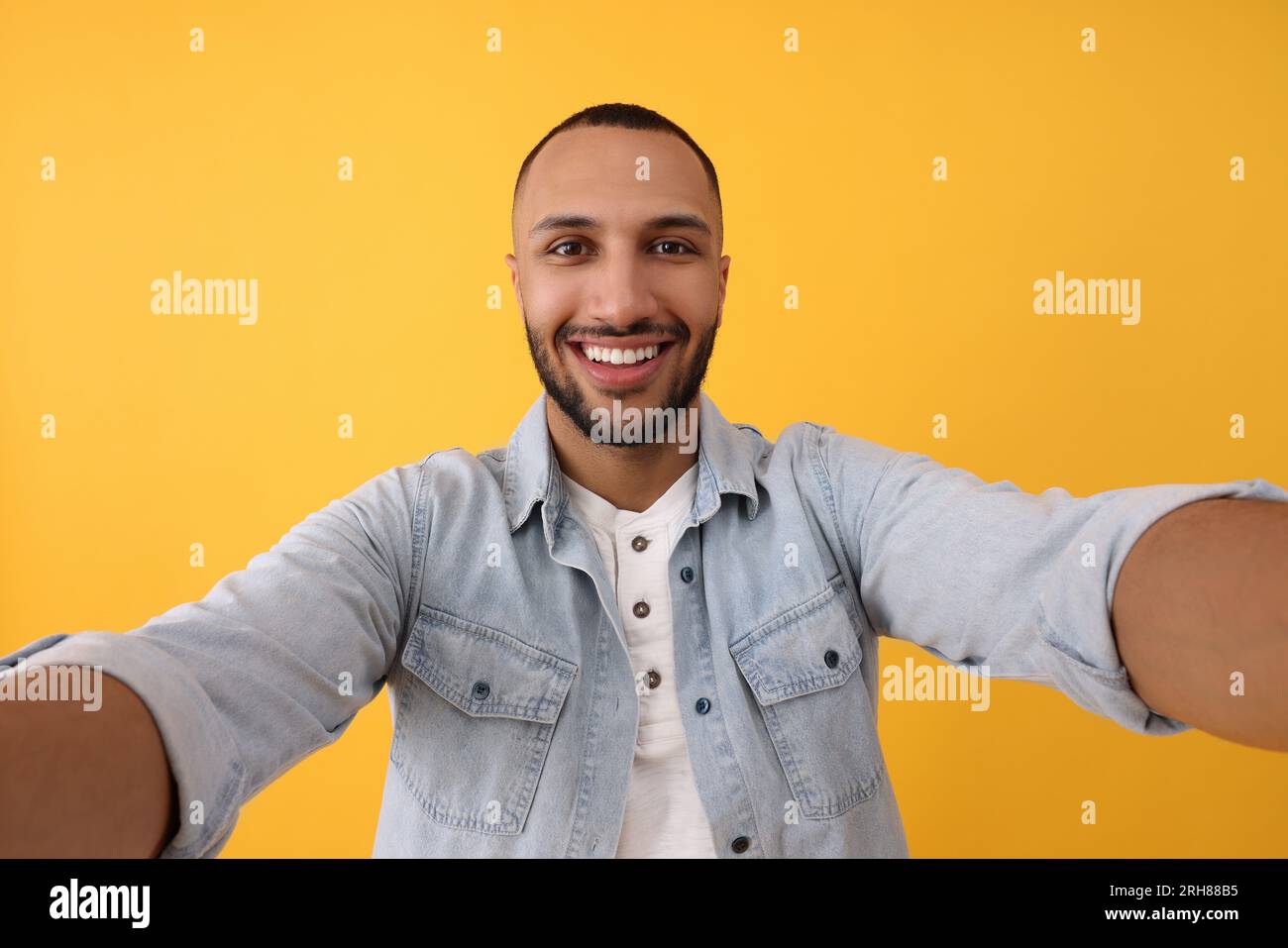 Giovane sorridente che scatta selfie su sfondo giallo Foto Stock