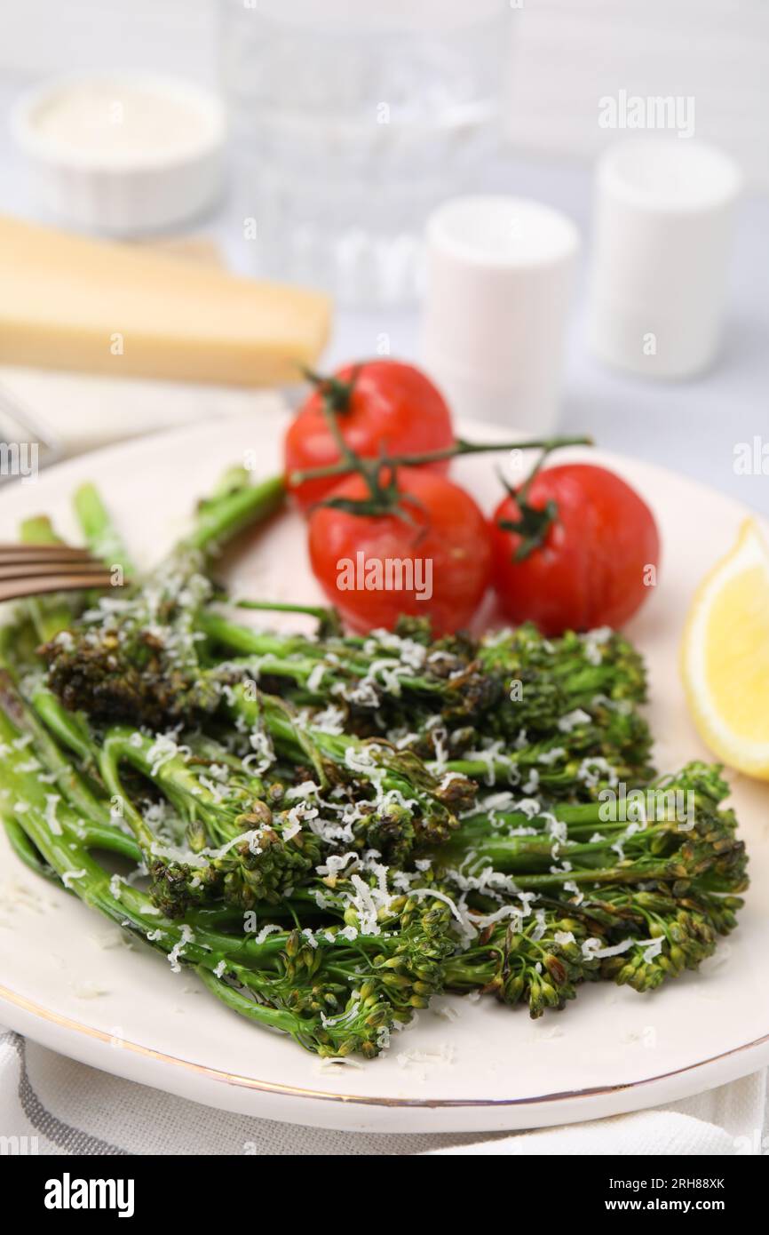 Gustosi broccolini cotti con formaggio e pomodori su piatto, primo piano Foto Stock