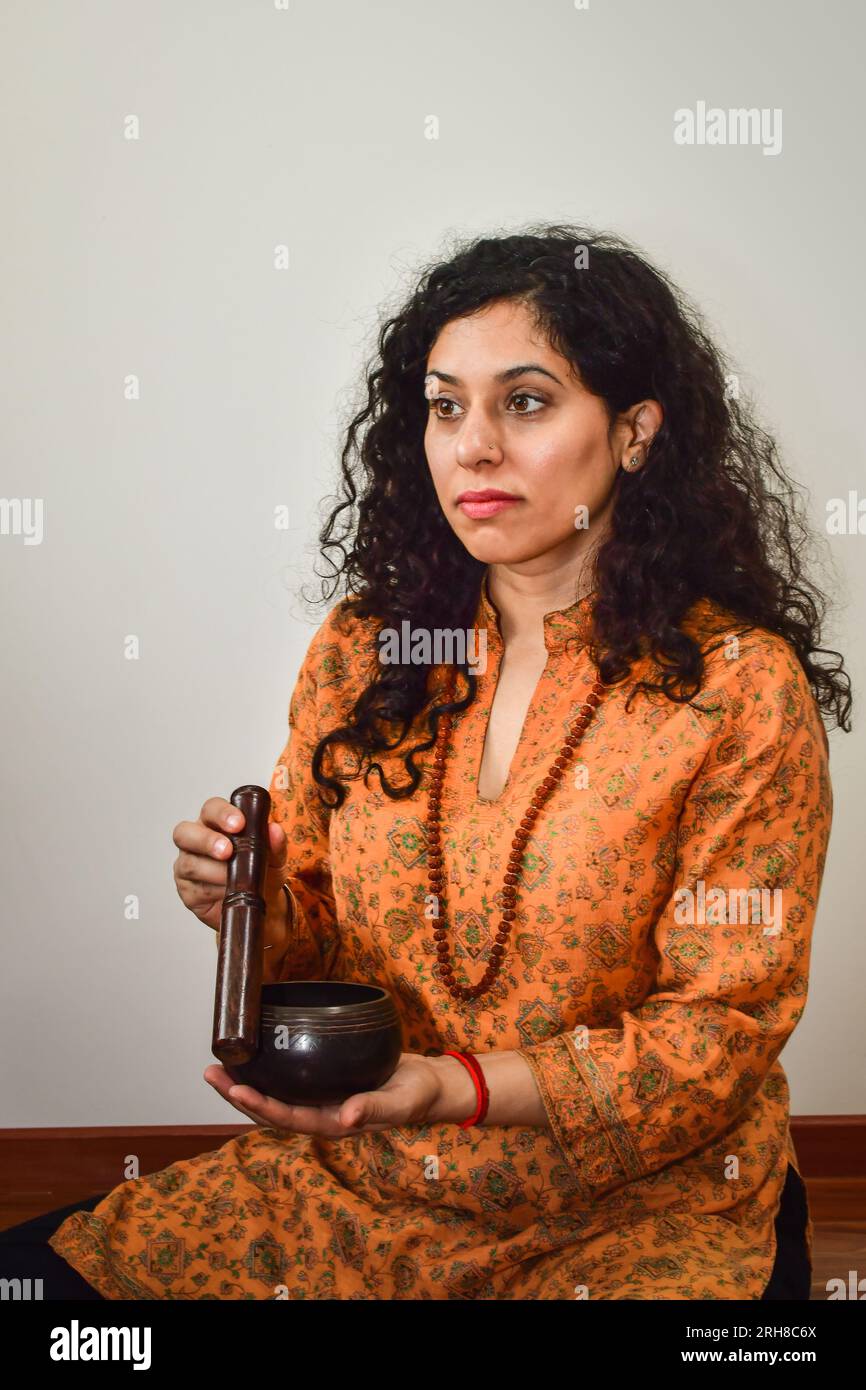 Una donna che pratica meditazione e guarigione con una ciotola tibetana. Foto Stock