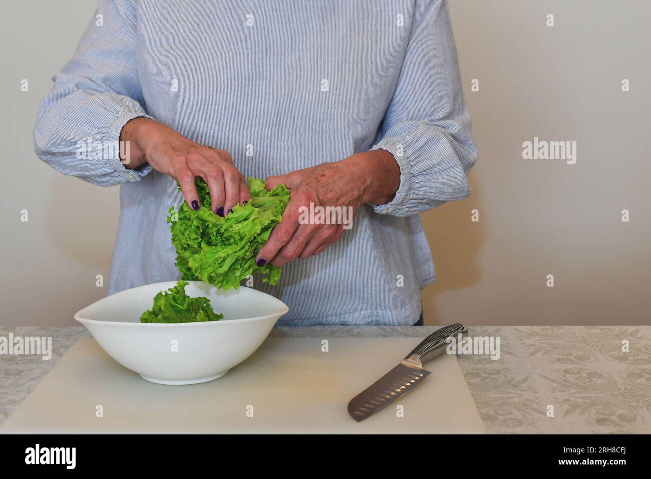 Cucina, cibo e concetto di casa. Una donna lacrime una foglia di insalata. Foto Stock