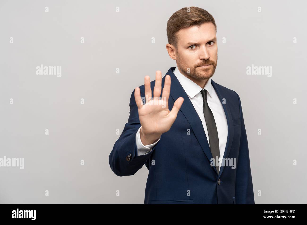 Ritratto di un uomo d'affari serio che mostra il gesto della mano di stop su sfondo grigio. Foto Stock