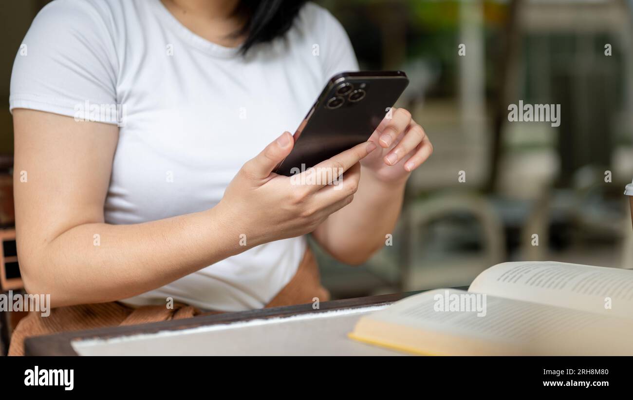 Immagine ravvicinata di una freelance che scrive sullo schermo dello smartphone, chatta, invia messaggi mentre si siede a un tavolo in un bar. Foto Stock