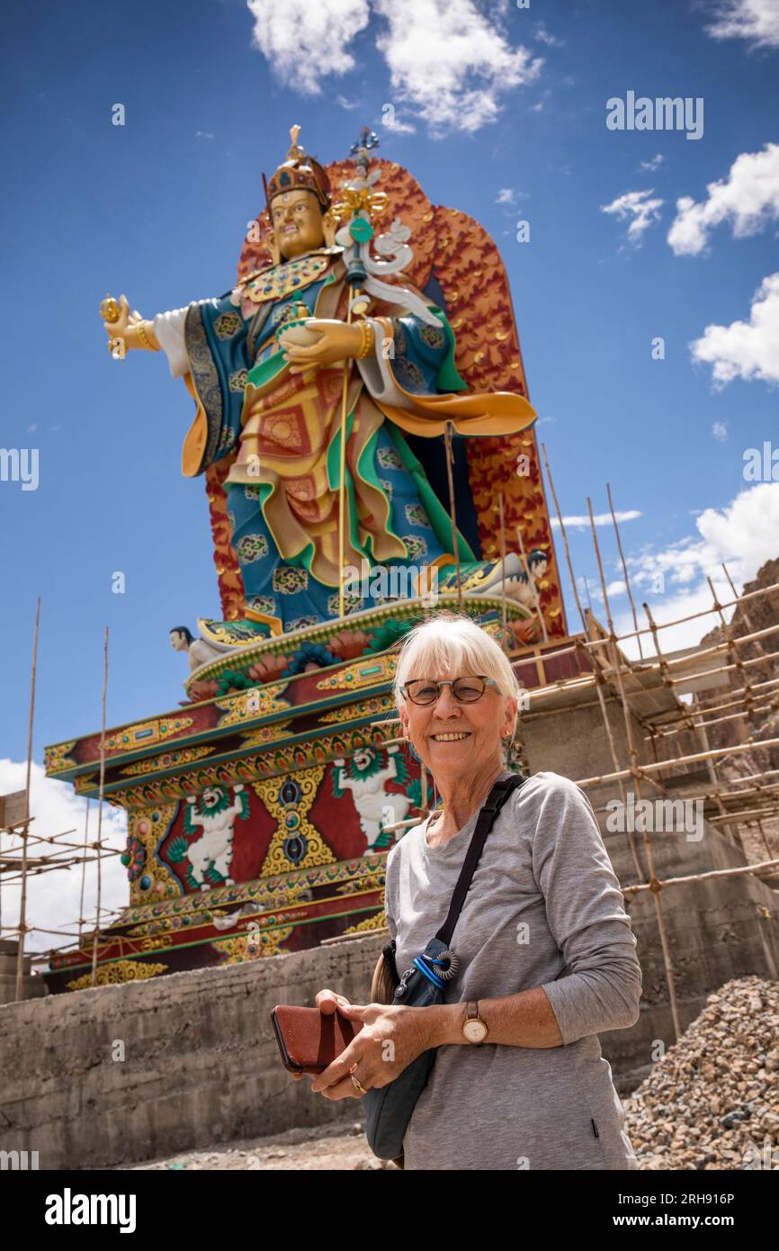 India, Jammu e Kashmir, Ladakh, Bodhkharbu, anziana turista sotto la statua gigante di Guru Padmasambhava in fase di ristrutturazione Foto Stock