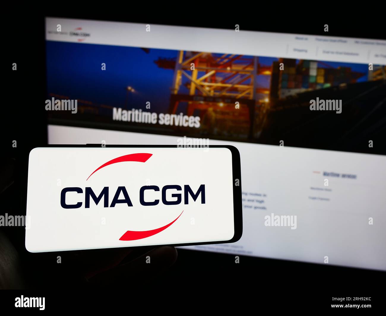 Persona in possesso di un cellulare con il logo della società di logistica francese CMA CGM S.A. sullo schermo di fronte alla pagina Web aziendale. Concentrarsi sul display del telefono. Foto Stock