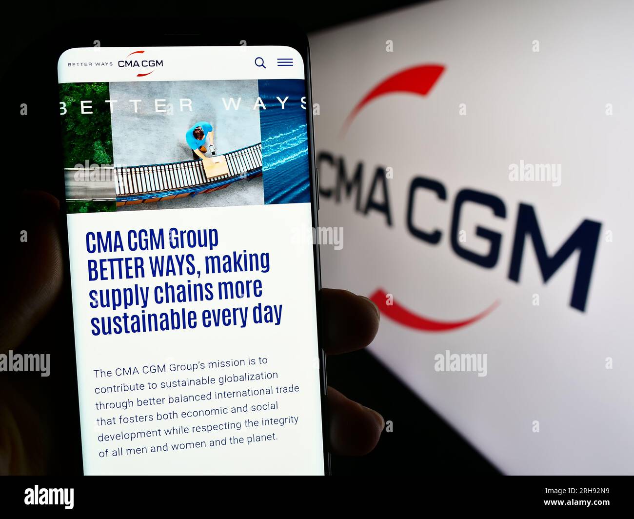 Persona che possiede uno smartphone con il sito web della società di logistica francese CMA CGM SA sullo schermo davanti al logo. Concentrarsi sul centro del display del telefono. Foto Stock