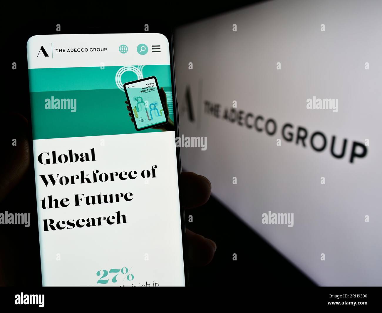 Persona in possesso di un cellulare con pagina Web della società delle risorse umane Adecco Group AG sullo schermo davanti al logo. Concentrarsi sul centro del display del telefono. Foto Stock