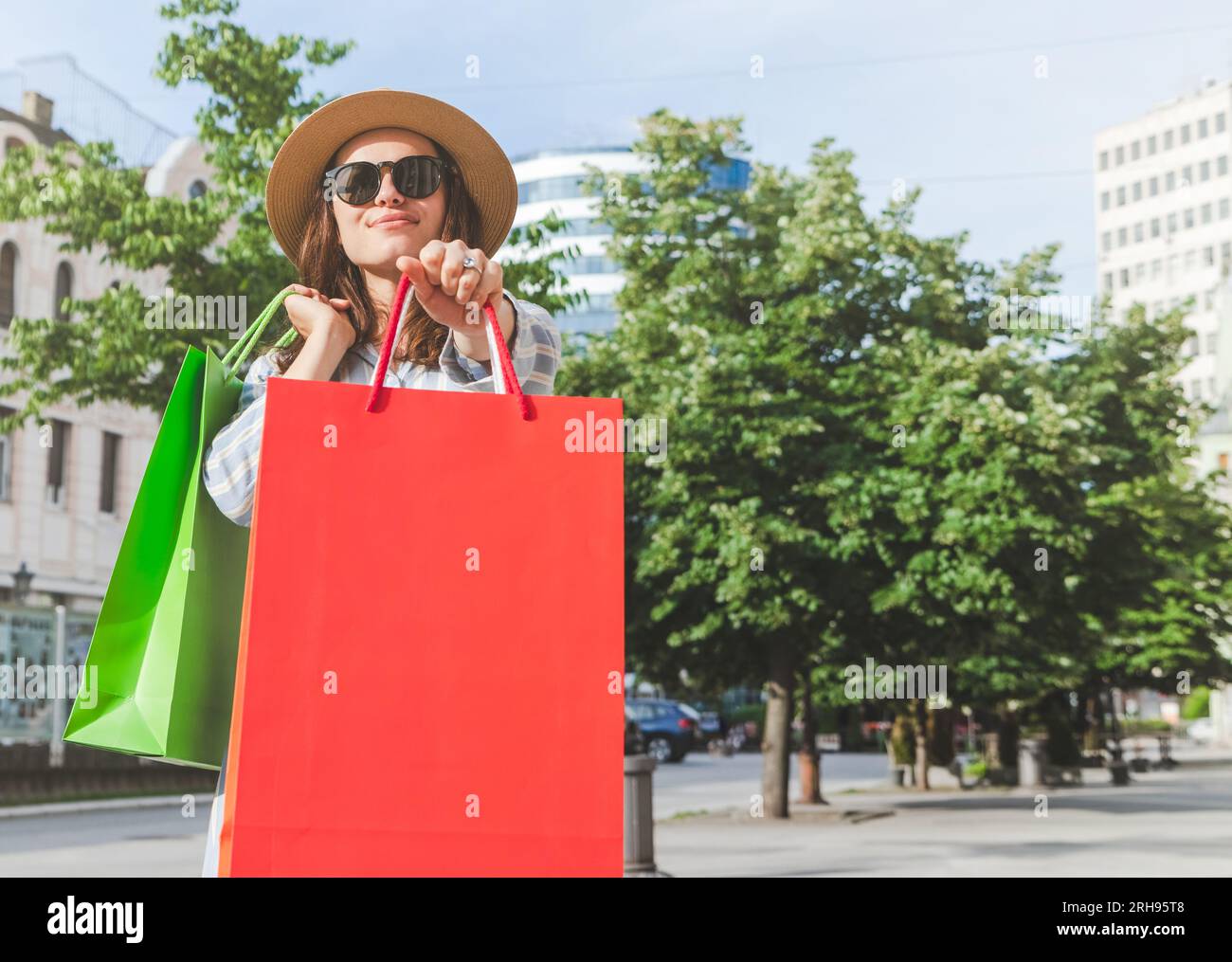 Giovane donna alla moda che fa shopping in città, con borse colorate in mano. Foto Stock