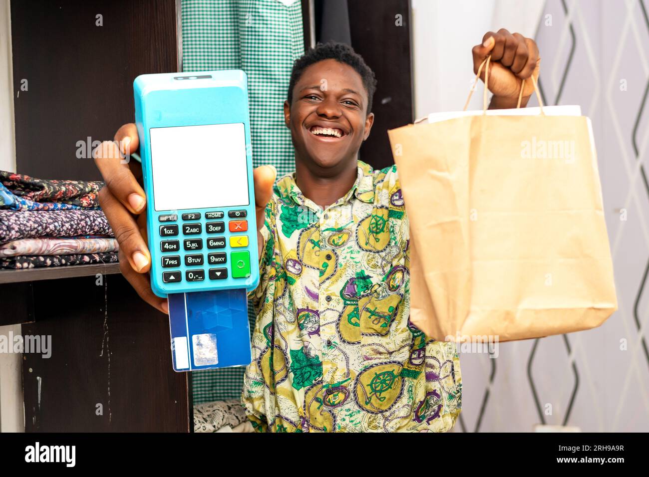 Foto del corriere africano nero che tiene la borsa della spesa e un terminale POS Foto Stock