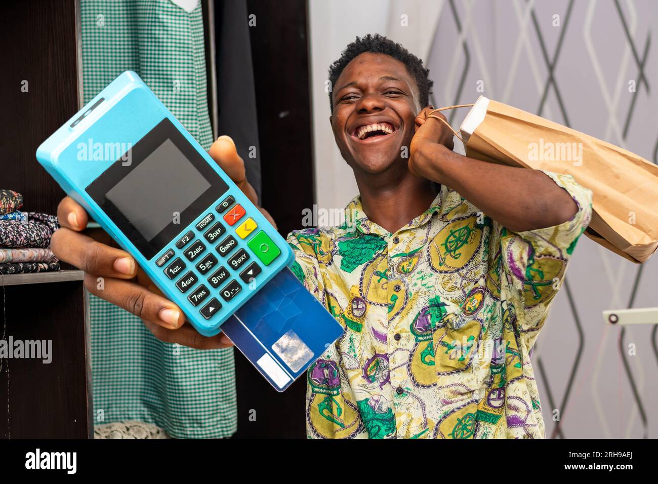 Foto del corriere africano nero che tiene la borsa della spesa e un terminale POS Foto Stock