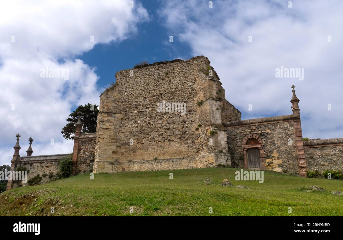 Vista delle rovine del cimitero gotico nella città cantabrica di Comillas, con un prato verde e un cielo blu con nuvole. Foto Stock
