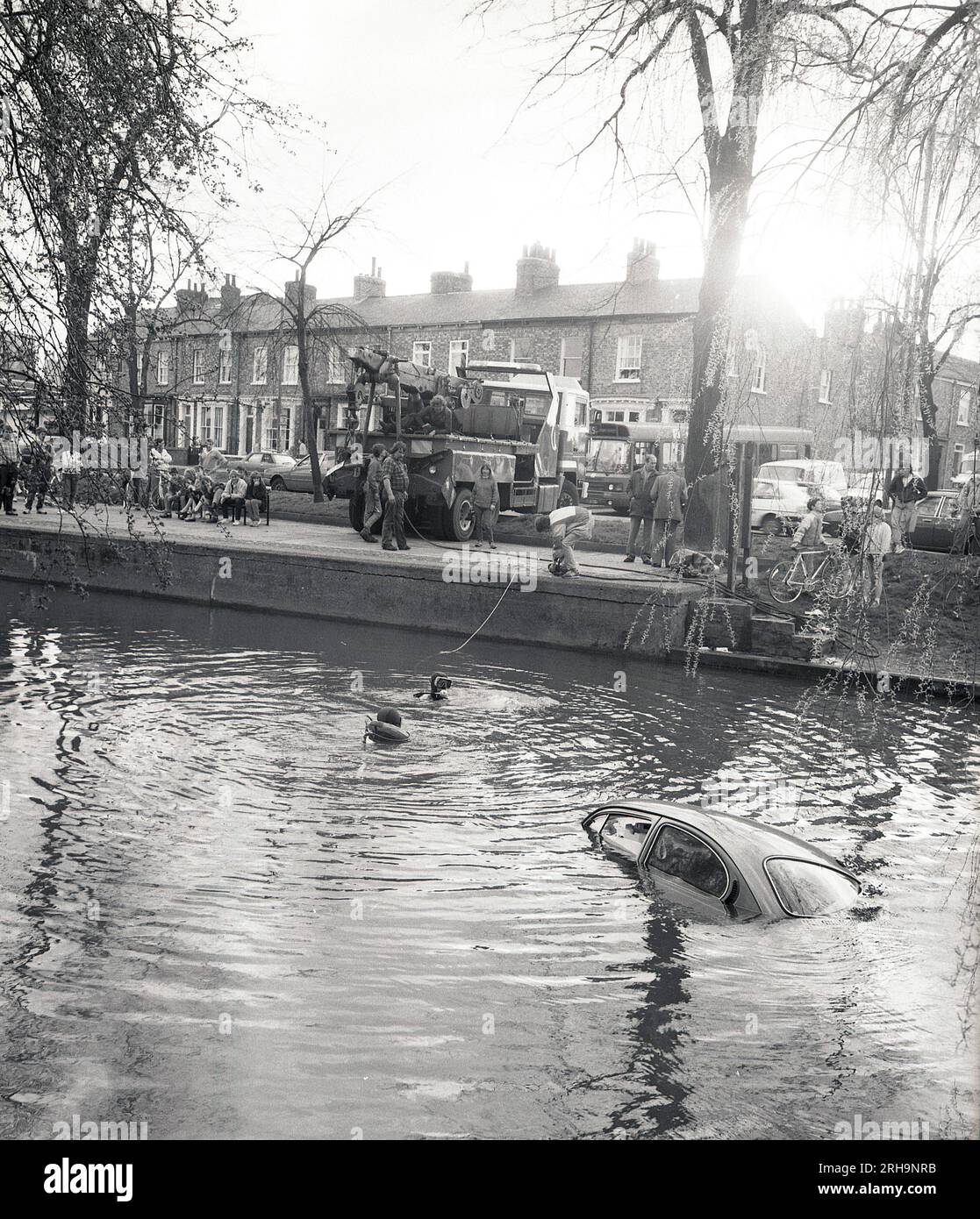 1987, un'auto che viene estratta da un fiume urbano, Inghilterra, Regno Unito. Subacquei in acqua che assistono al recupero. Foto Stock