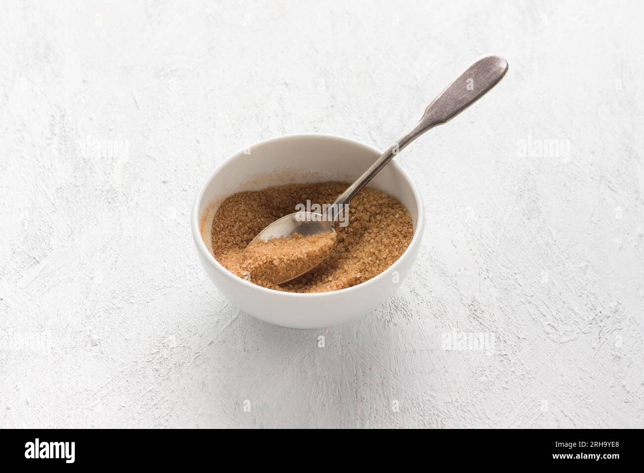 Recipiente bianco con una miscela di zucchero e cannella per un delizioso dessert su sfondo grigio chiaro, fase di cottura. Foto Stock