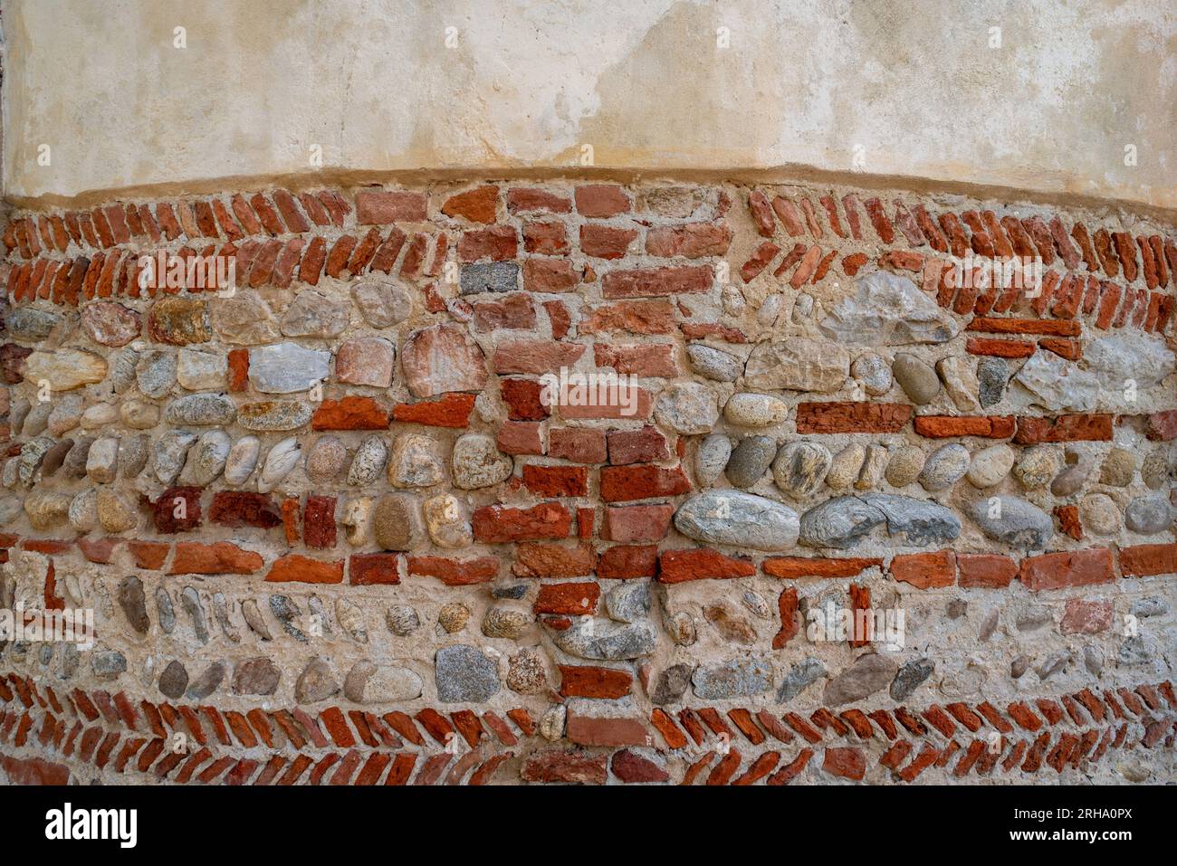 Antica parete a forma curva strutturata in tonalità e mattoni rossi disposti a spina di pesce con parte superiore intonacata, sfondo con spazio per la copia Foto Stock
