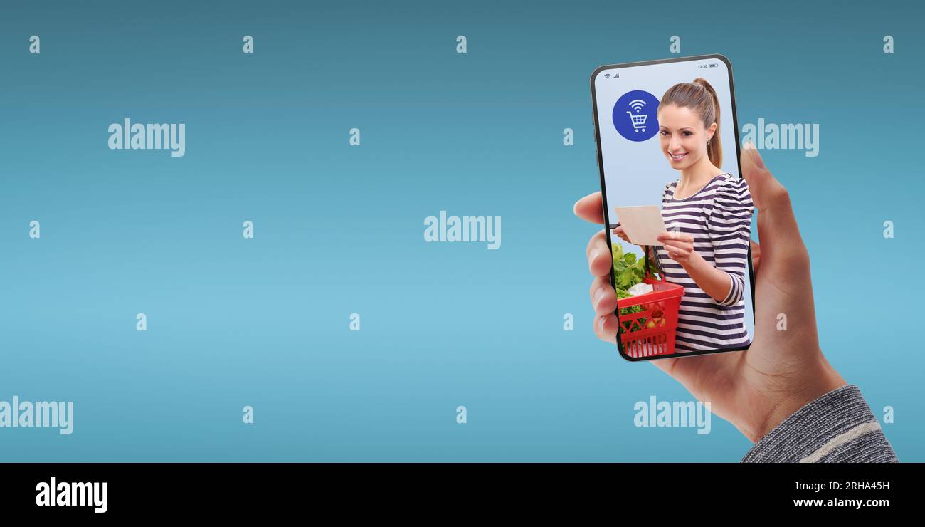 App online per la spesa di alimentari: Cliente felice che ha un carrello pieno e una lista di alimentari Foto Stock