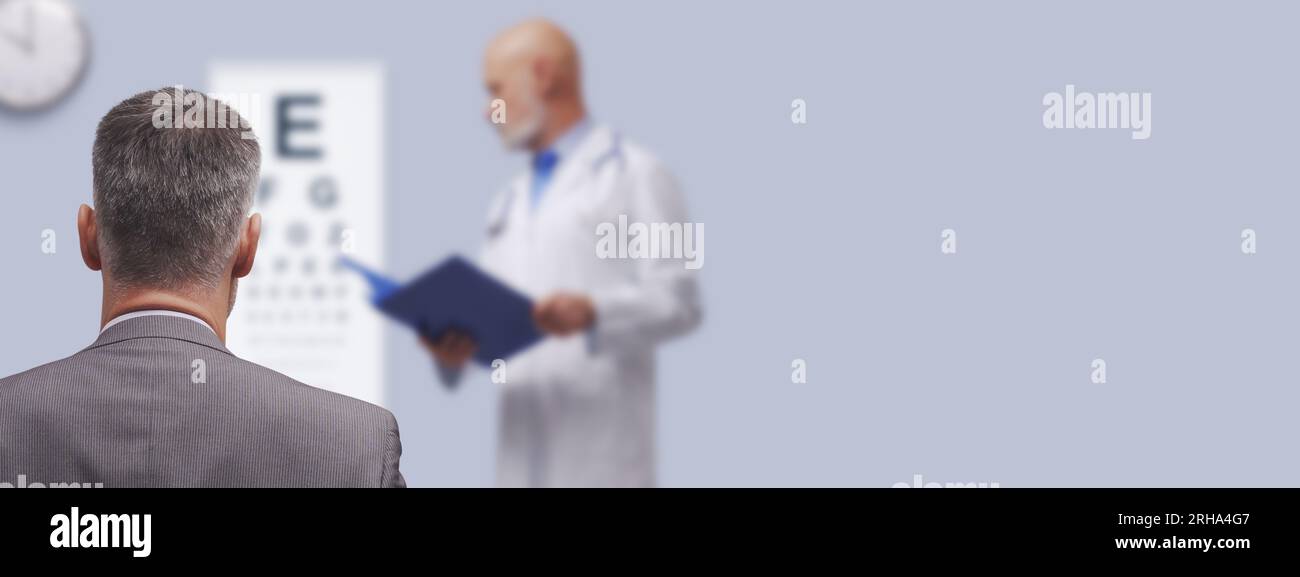 Oftalmologo che esegue un esame oculistico nel suo ufficio, il paziente sta guardando il grafico oculistico, il concetto oculistico, lo spazio di copia Foto Stock