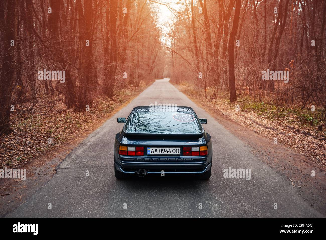 Videogame di corse ma nella vita reale: Porsche 944 blu scuro su una strada stretta attraverso una foresta. Mi piaceva giocare a NFS quando era piccolo, ora ricreando momenti Foto Stock