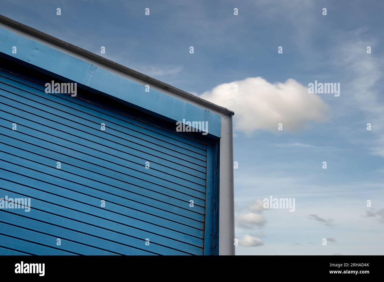 unità magazzino per la costruzione di terreni industriali con porta a rulli contro un cielo blu Foto Stock