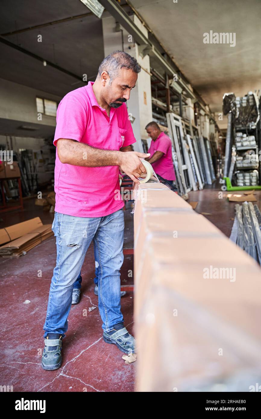 Lavoratori che imballano la scatola di cartone in magazzino per la spedizione. un operatore chiude una scatola di cartone con nastro adesivo in un magazzino. Foto Stock