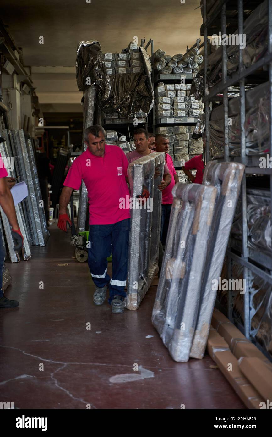 Lavoratori che confezionano fogli di vetro in magazzino. lavoratore che spedisce la finestra in vetro. lavoratore che indossa giubbotto di sicurezza e casco. Foto Stock