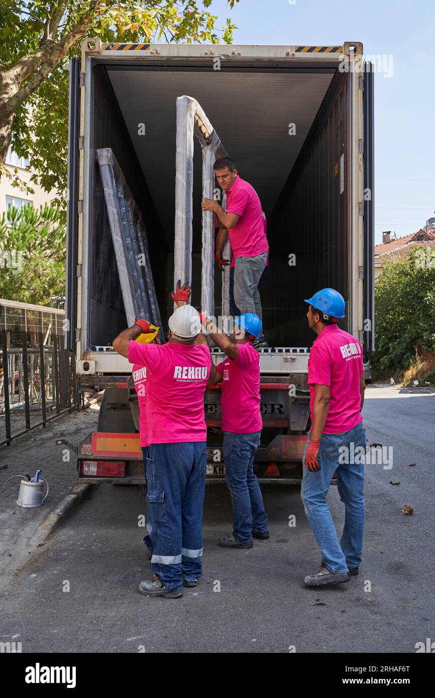 Lavoratori che confezionano fogli di vetro in magazzino. lavoratore che spedisce la finestra in vetro. lavoratore che indossa giubbotto di sicurezza e casco. Foto Stock