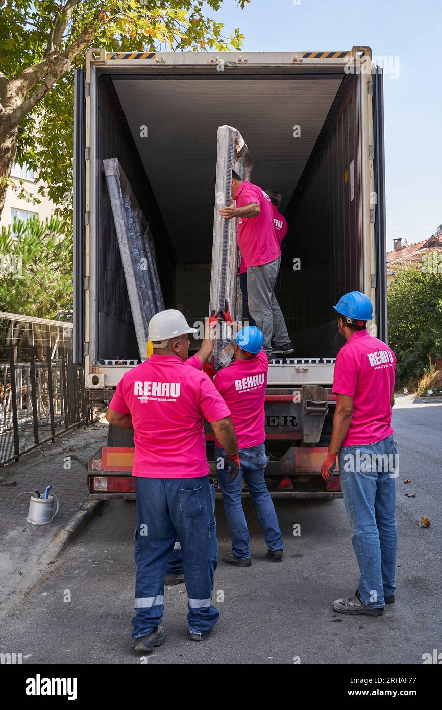 Lavoratori che confezionano fogli di vetro in magazzino. lavoratore che spedisce la finestra in vetro. lavoratore che indossa giubbotto di sicurezza e casco. Foto Stock
