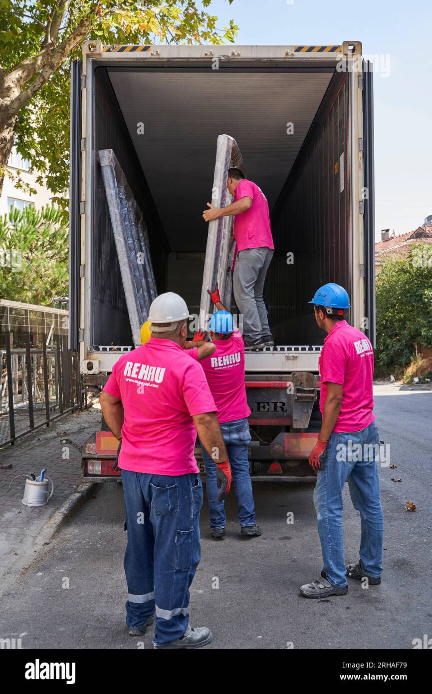 Lavoratori che confezionano fogli di vetro in magazzino. lavoratore che spedisce la finestra in vetro. lavoratore che indossa giubbotto di sicurezza e casco. Foto Stock