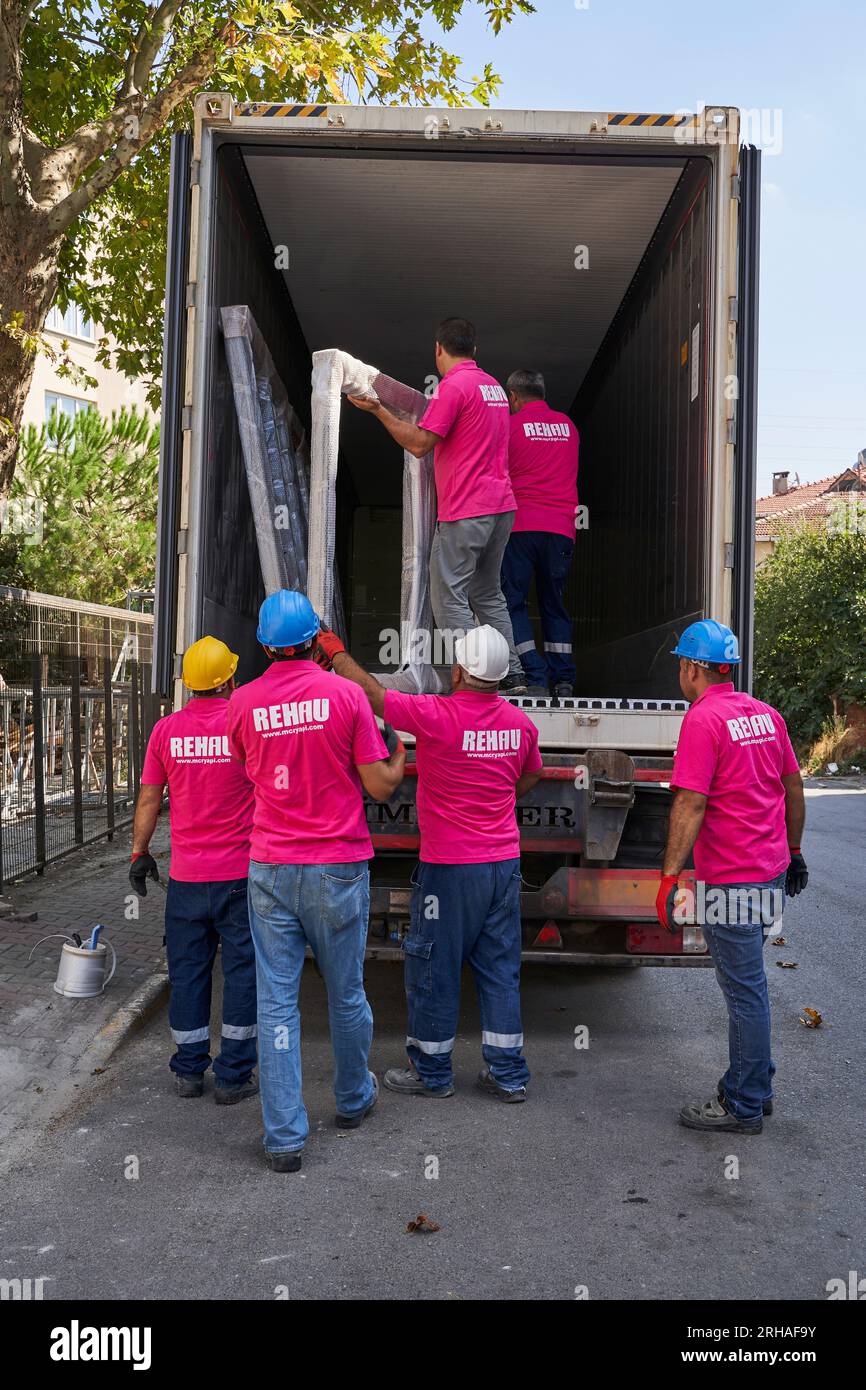 Lavoratori che confezionano fogli di vetro in magazzino. lavoratore che spedisce la finestra in vetro. lavoratore che indossa giubbotto di sicurezza e casco. Foto Stock