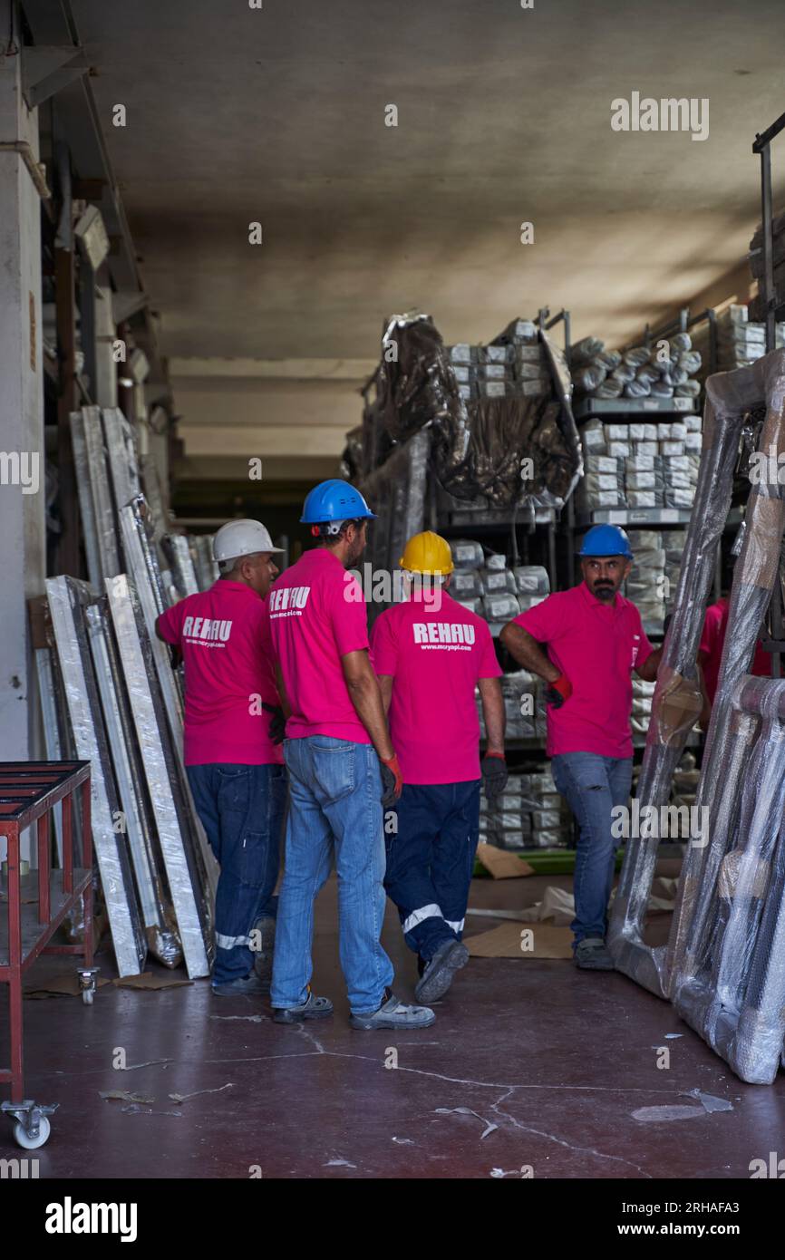 Lavoratori che confezionano fogli di vetro in magazzino. lavoratore che spedisce la finestra in vetro. lavoratore che indossa giubbotto di sicurezza e casco. Foto Stock