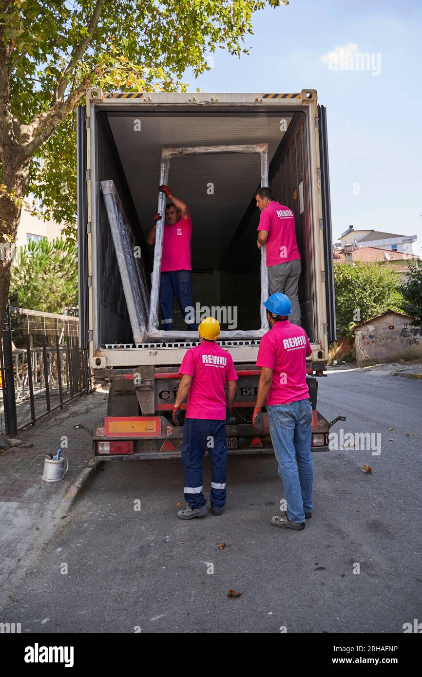 Lavoratori che confezionano fogli di vetro in magazzino. lavoratore che spedisce la finestra in vetro. lavoratore che indossa giubbotto di sicurezza e casco. Foto Stock