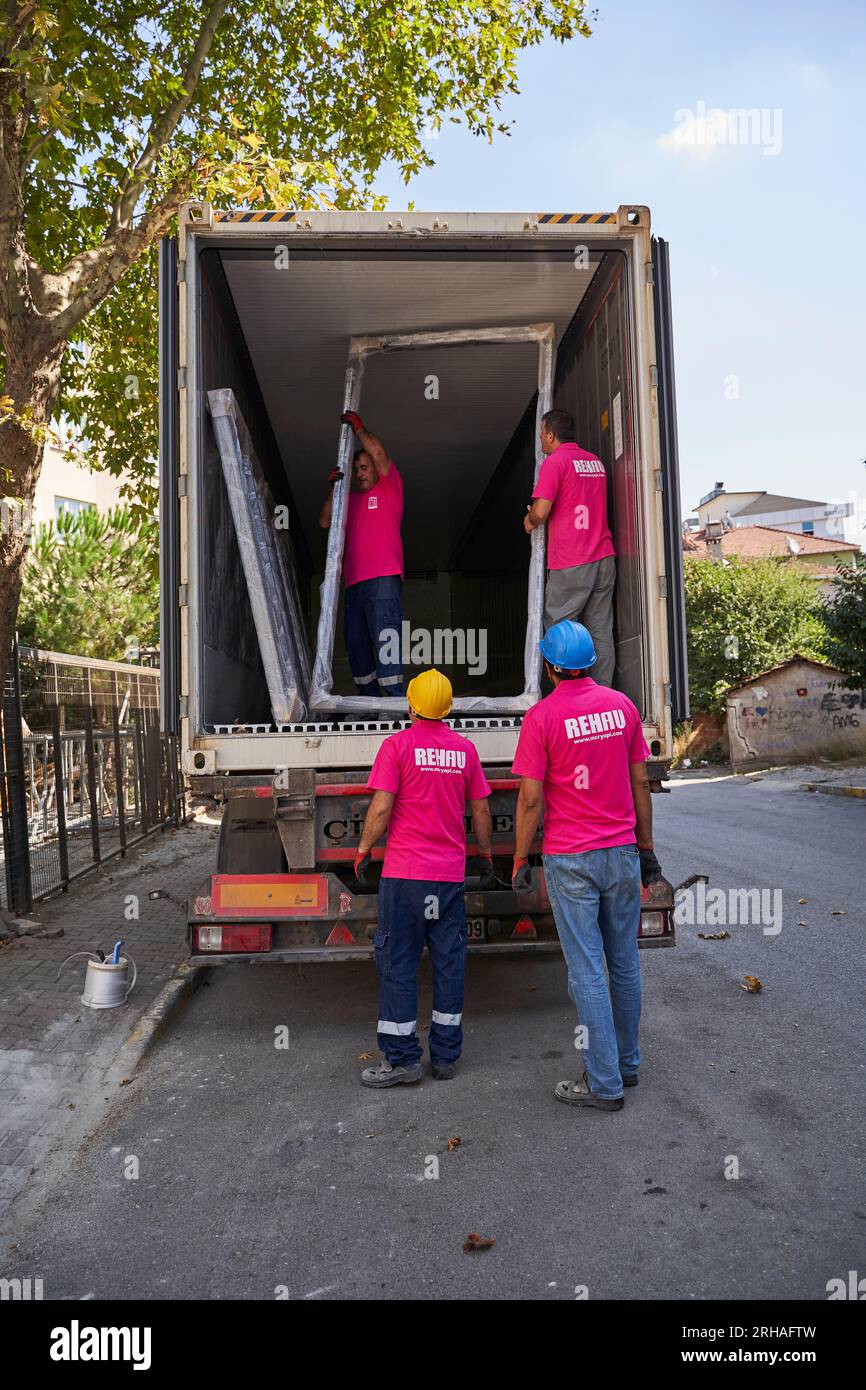 Lavoratori che confezionano fogli di vetro in magazzino. lavoratore che spedisce la finestra in vetro. lavoratore che indossa giubbotto di sicurezza e casco. Foto Stock