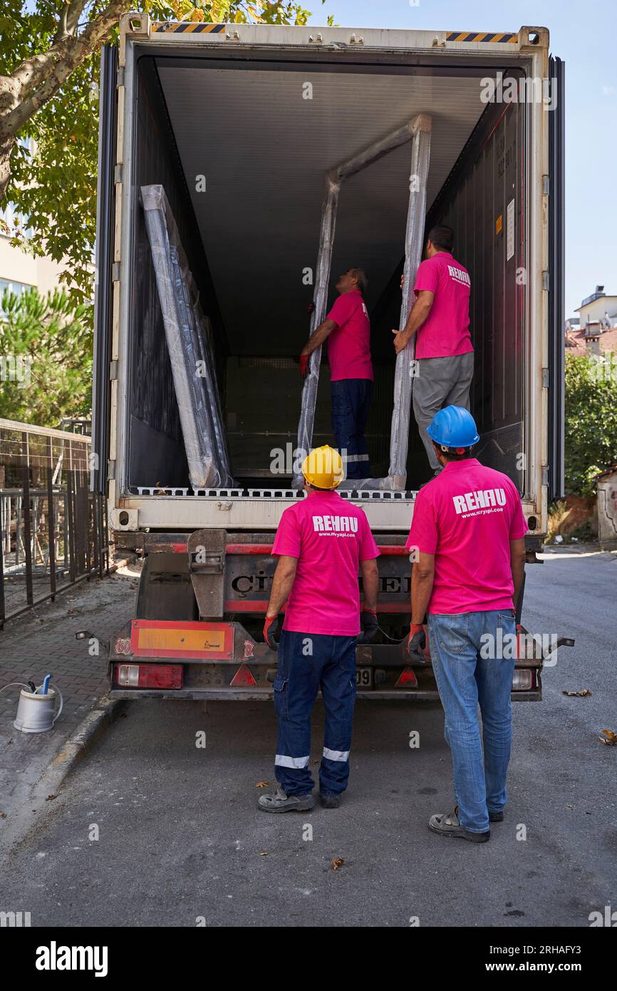 Lavoratori che confezionano fogli di vetro in magazzino. lavoratore che spedisce la finestra in vetro. lavoratore che indossa giubbotto di sicurezza e casco. Foto Stock