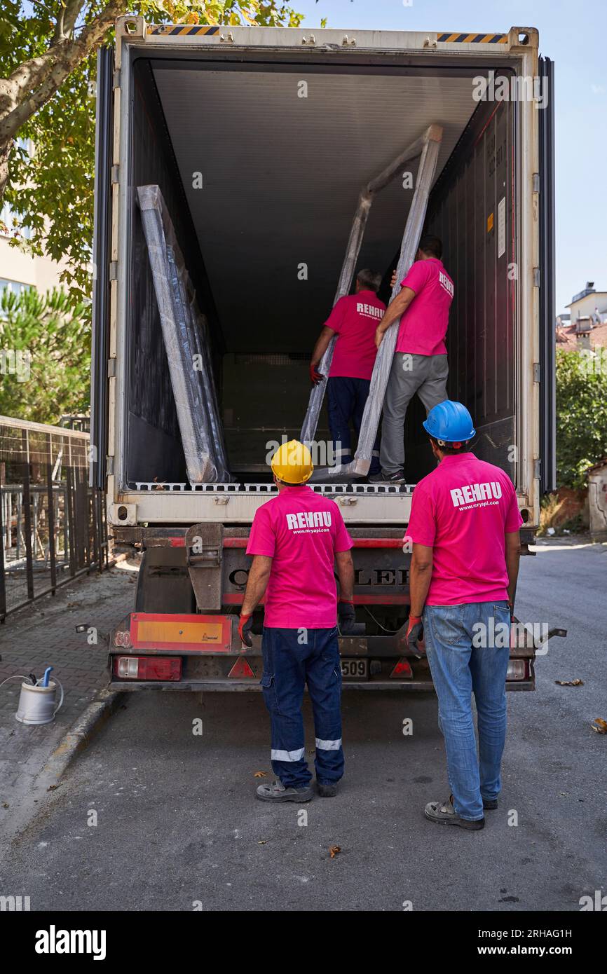 Lavoratori che confezionano fogli di vetro in magazzino. lavoratore che spedisce la finestra in vetro. lavoratore che indossa giubbotto di sicurezza e casco. Foto Stock