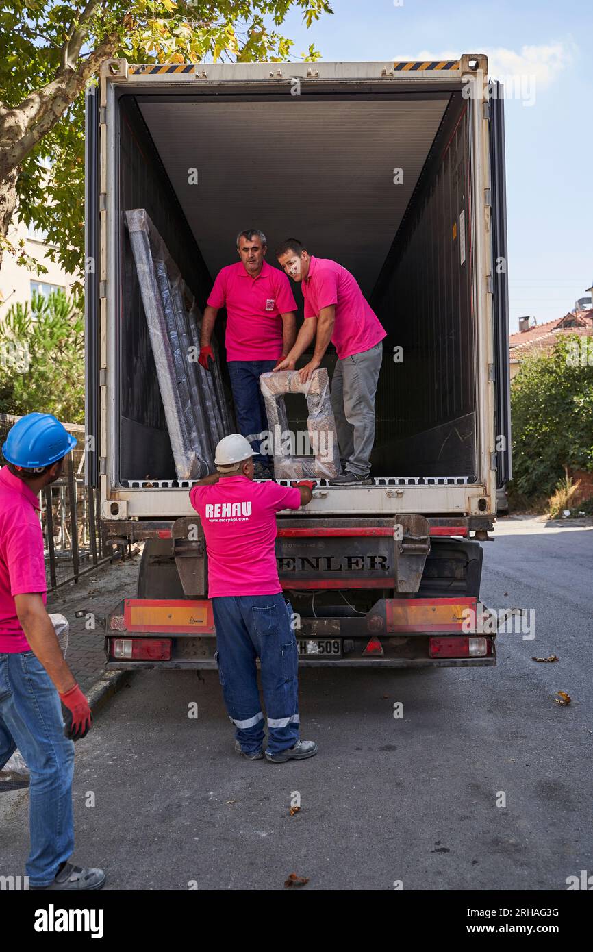 Lavoratori che confezionano fogli di vetro in magazzino. lavoratore che spedisce la finestra in vetro. lavoratore che indossa giubbotto di sicurezza e casco. Foto Stock