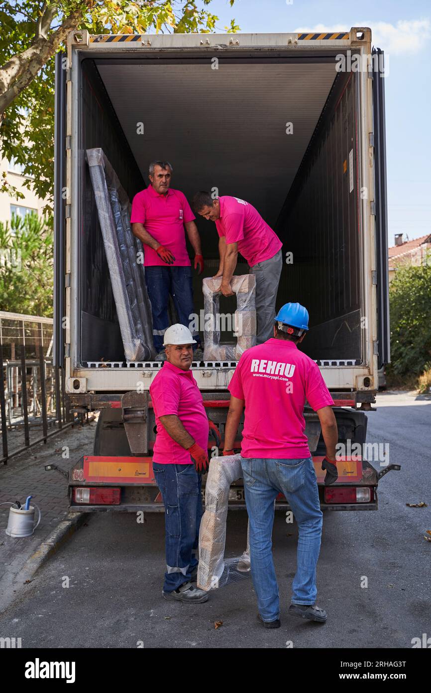 Lavoratori che confezionano fogli di vetro in magazzino. lavoratore che spedisce la finestra in vetro. lavoratore che indossa giubbotto di sicurezza e casco. Foto Stock
