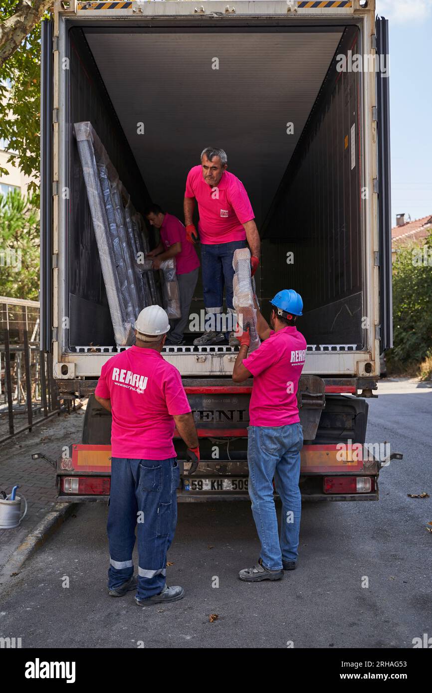 Lavoratori che confezionano fogli di vetro in magazzino. lavoratore che spedisce la finestra in vetro. lavoratore che indossa giubbotto di sicurezza e casco. Foto Stock