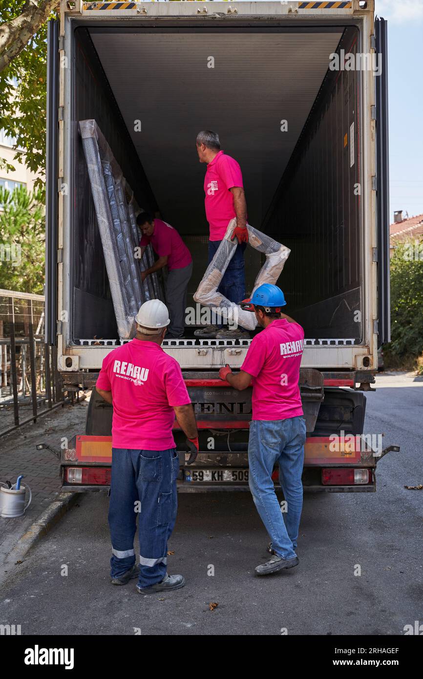 Lavoratori che confezionano fogli di vetro in magazzino. lavoratore che spedisce la finestra in vetro. lavoratore che indossa giubbotto di sicurezza e casco. Foto Stock