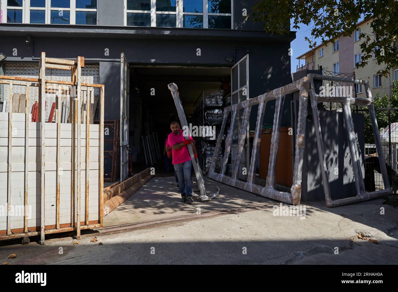 Lavoratori che confezionano fogli di vetro in magazzino. lavoratore che spedisce la finestra in vetro. lavoratore che indossa giubbotto di sicurezza e casco. Foto Stock