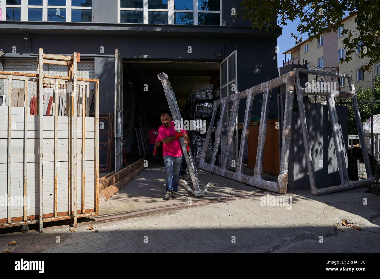 Lavoratori che confezionano fogli di vetro in magazzino. lavoratore che spedisce la finestra in vetro. lavoratore che indossa giubbotto di sicurezza e casco. Foto Stock