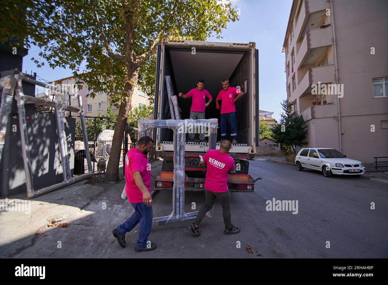 Lavoratori che confezionano fogli di vetro in magazzino. lavoratore che spedisce la finestra in vetro. lavoratore che indossa giubbotto di sicurezza e casco. Foto Stock