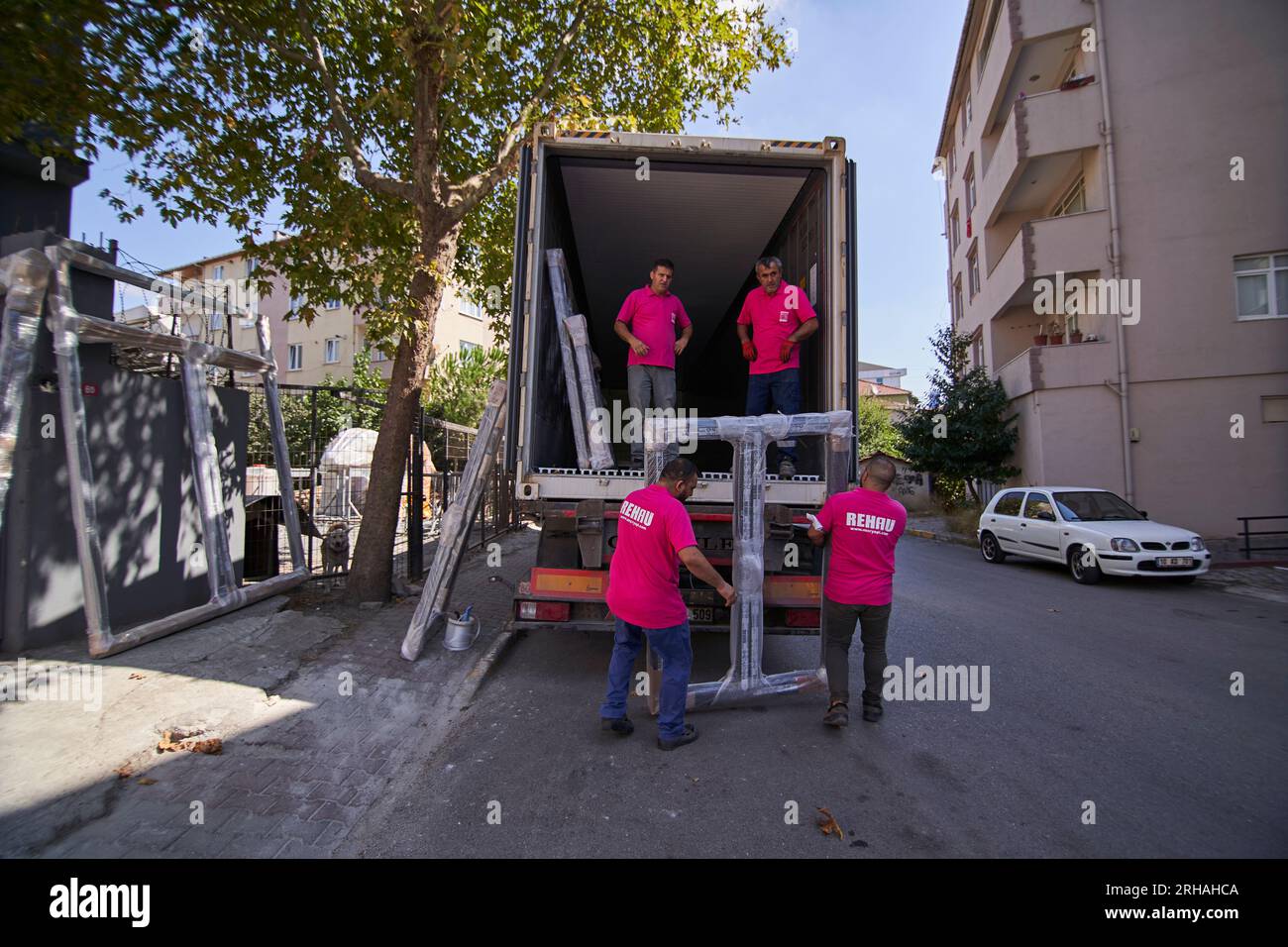 Lavoratori che confezionano fogli di vetro in magazzino. lavoratore che spedisce la finestra in vetro. lavoratore che indossa giubbotto di sicurezza e casco. Foto Stock