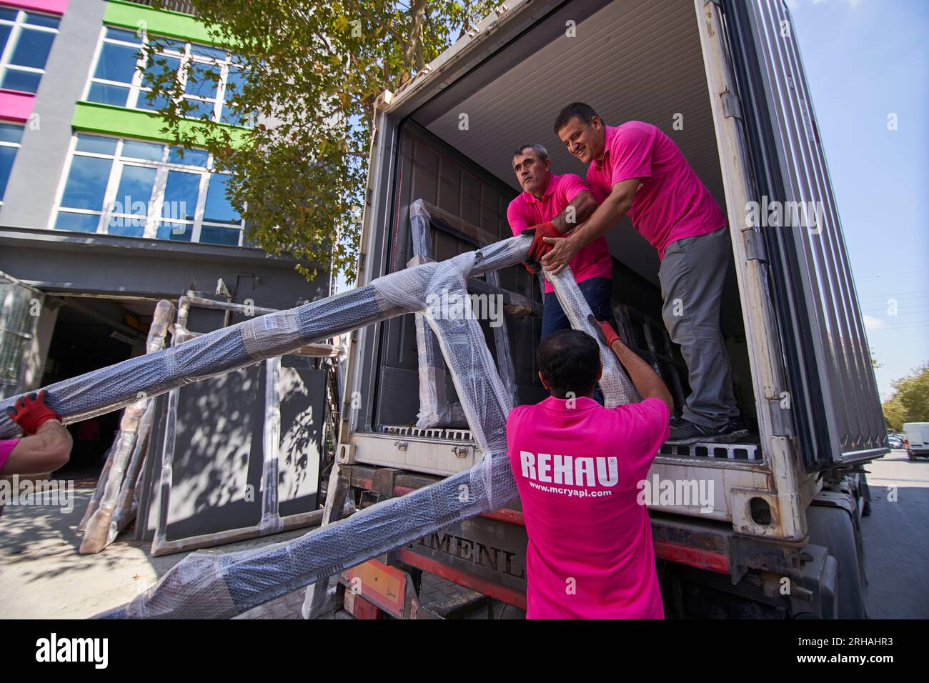 Lavoratori che confezionano fogli di vetro in magazzino. lavoratore che spedisce la finestra in vetro. lavoratore che indossa giubbotto di sicurezza e casco. Foto Stock