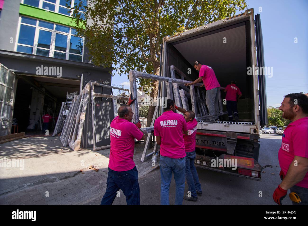 Lavoratori che confezionano fogli di vetro in magazzino. lavoratore che spedisce la finestra in vetro. lavoratore che indossa giubbotto di sicurezza e casco. Foto Stock