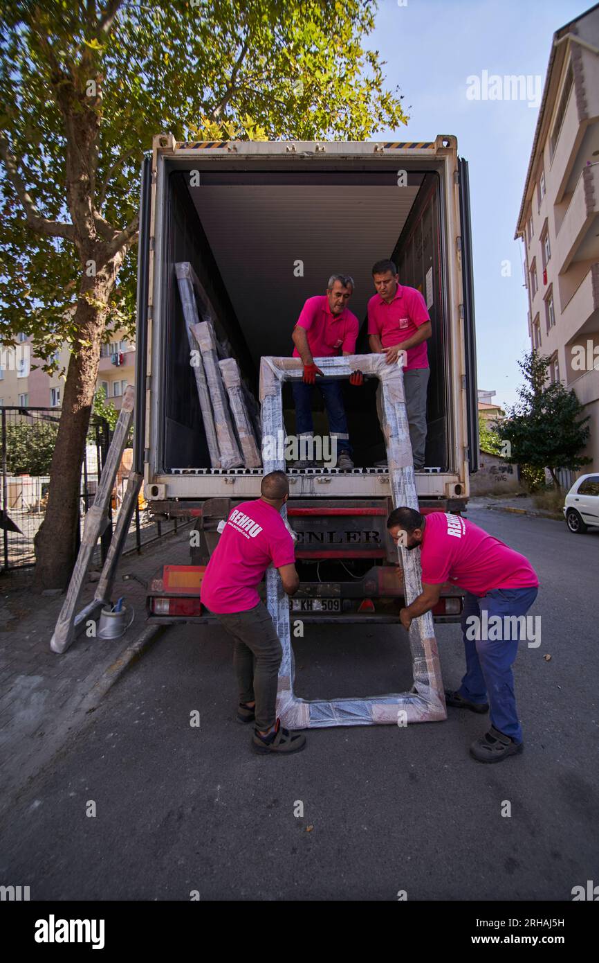 Lavoratori che confezionano fogli di vetro in magazzino. lavoratore che spedisce la finestra in vetro. lavoratore che indossa giubbotto di sicurezza e casco. Foto Stock